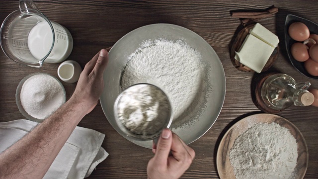 男人的手揉面团。制作美味佳肴或甜点的过程在桌子上烘焙的原料。在烹饪时，最好安排一张木桌。视频素材