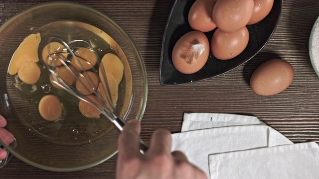 男人的手揉面团。制作美味佳肴或甜点的过程在桌子上烘焙的原料。在烹饪时，最好安排一张木桌。视频素材