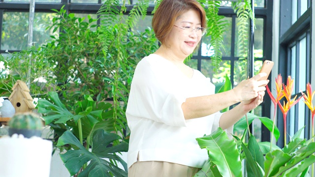 高级妇女在温室里讲手机。视频素材