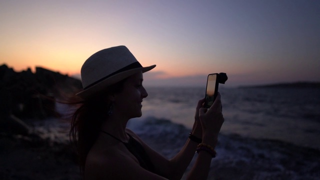 在海滩上拍摄日落的女人视频素材