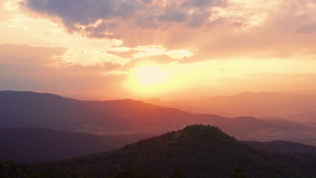 镜头光晕的太阳通过杉树顶部在全景山景观在日落和明亮的圆盘太阳在早晨在夏季对蓝色的天空鸟瞰无人机向前。大自然。旅行视频素材