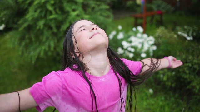 肖像快乐湿孩子在雨中花园在炎热的夏天视频素材