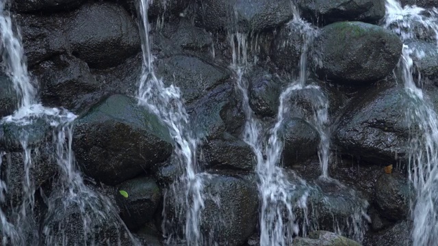 一段近距离静止的视频显示，一股水流从威斯康辛州一名男子的脸上倾泻而下，由石头和岩石制成的瀑布，水流从悬崖上飞溅而下。视频素材