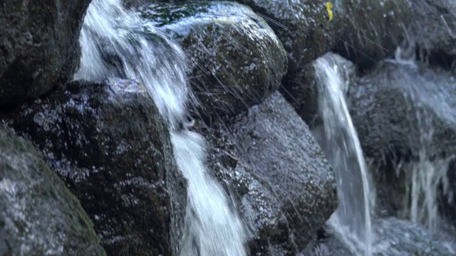 特写镜头下的水流动的岩石潮湿的表面在威斯康星州的瀑布与草生长在顶部。视频素材