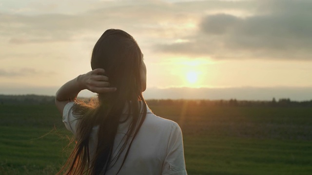 长发女孩的背影肖像在乡村日落背景复制文本空间。女人的女人独自站在自然黄昏的光。护发造型产品化妆品视频素材