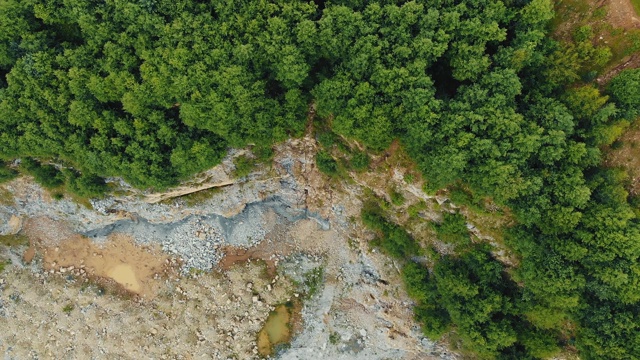 鸟瞰图在山顶采石场开采的石头。岩石地形和悬崖在山的边缘，绿色的树木生长。视频素材