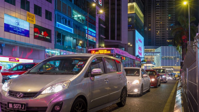 在吉隆坡的道路上的运动汽车在亭子和商店前的夜晚视频素材