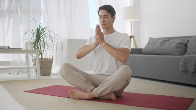 单身男人在家里做瑜伽，保持他的眼睛闭着慢慢呼吸。在家运动和健康的生活方式，活动，健身和锻炼。室内训练和家庭运动视频素材