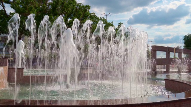 城市喷泉在一个明媚的夏日，人们走在后面，公共空间视频素材