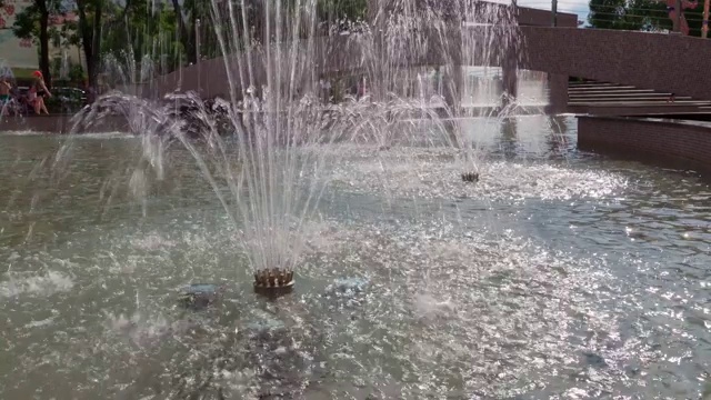 城市喷泉在一个明媚的夏日，人们走在后面，公共空间视频素材