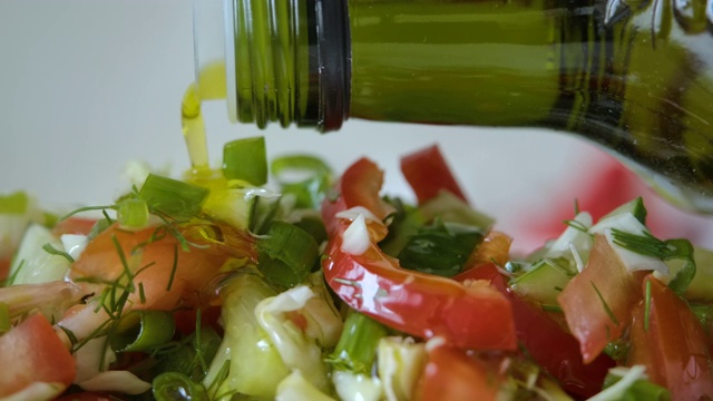 蔬菜新鲜沙拉食品健康餐地中海厨房素食饮食橄榄油。在新鲜沙拉上倒入橄榄油。近距离的健康午餐，彩色食物洋葱黄瓜萝卜。慢动作视频素材