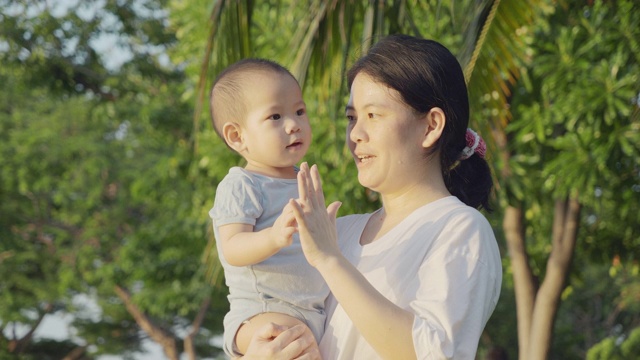 4K，妈妈抱着他的儿子在日落公园。视频素材