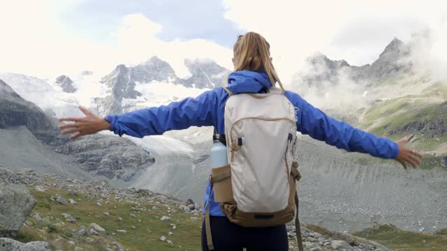 徒步女孩举起手臂庆祝风景优美的风景，享受假期旅行冒险的自然瑞士莫瑞冰川视频素材