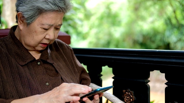 使用智能手机的亚洲年长女性。手持手机的老年女性。成熟的退休生活视频素材