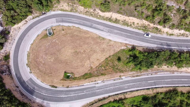 鸟瞰图蜿蜒的道路在高山口槽绿色松林。高质量的画面视频素材