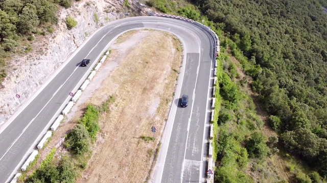 鸟瞰图蜿蜒的道路在高山口槽绿色松林。高质量的画面视频素材