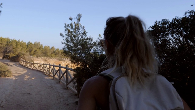 年轻女子在悬崖上欣赏日落的自然美景，并欣赏迷人的海景视频素材