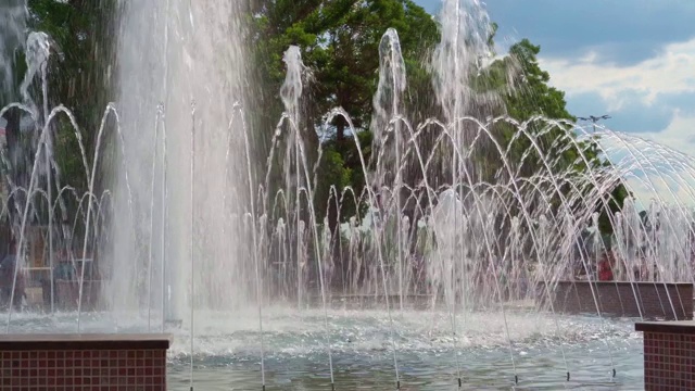 城市喷泉在一个明媚的夏日，人们走在后面，公共空间视频素材