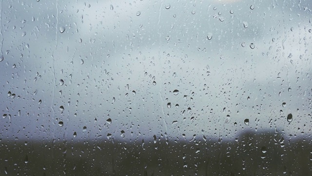 模糊背景下的雨滴在窗户上的镜头，雨天，水滴在玻璃上视频素材