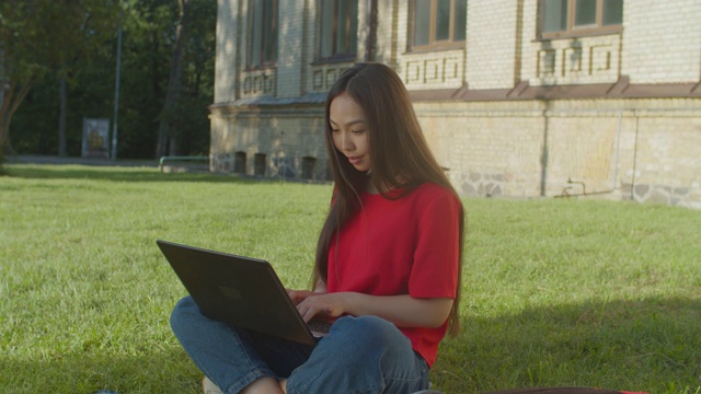 可爱的亚洲女学生在户外笔记本电脑上打字视频素材