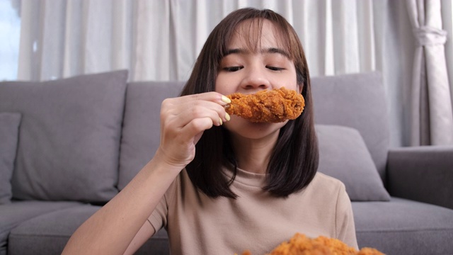 年轻的亚洲女性外卖吃垃圾食品鸡块鸡翅，女性享受安全的快餐外卖服务，并通过社交距离概念阻止冠状病毒的传播。视频素材