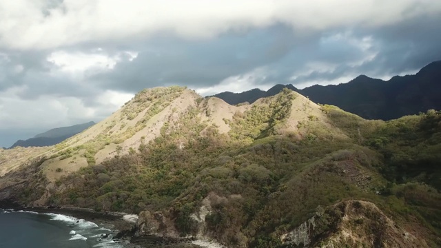 风景如画的科卡海滩。印度尼西亚弗洛雷斯的隐藏宝石。岸边漂着一条船。陡峭的山丘直通大海。公海上几乎没有巨石。夕阳的柔和色彩。视频素材