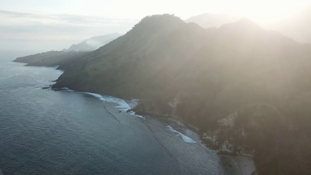 田园诗般的科卡海滩全景。印度尼西亚弗洛雷斯的隐藏宝石。海滩被海浪轻轻地冲刷着。陡峭的山丘直通大海。夕阳的柔和色彩。平静和冷静视频素材