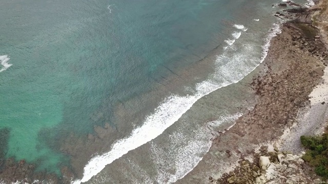 一架田园诗般的无人机拍摄到平静的海水涌向印度尼西亚弗洛雷斯的科卡海滩。海水呈清澈的绿松石色。珊瑚礁。平静和安宁。视频素材