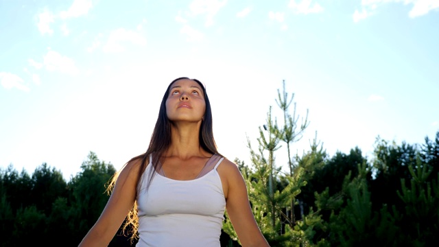 年轻女子在阳光灿烂的天空背景下进行户外瑜伽体式视频素材