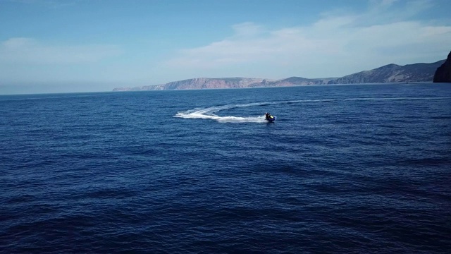 鸟瞰图的人骑水上摩托车与岩石和山丘的背景在黑海海滩在4k分辨率视频素材