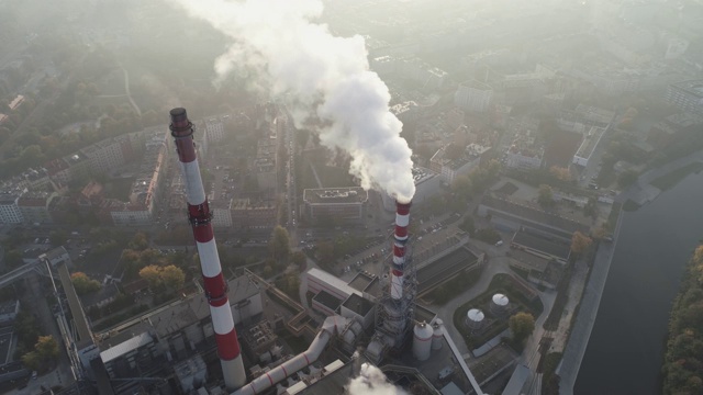 城市的空气污染。清晨城市上空的烟雾鸟瞰图，热电联产厂冒着烟的烟囱和城市的建筑物视频素材