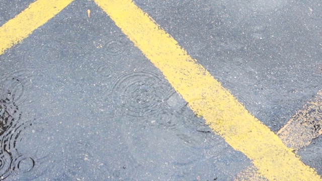 近距离观察雨滴落在街道上，雨滴落在被淹没的道路上视频素材