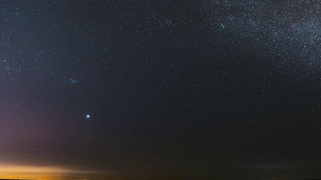 在早春的乡村田野景观上，夜晚星空与发光的星星。在银河系恒星之间的天空中行星金星的明亮辉光。夕阳下的天空。FullHD间隔拍摄视频素材