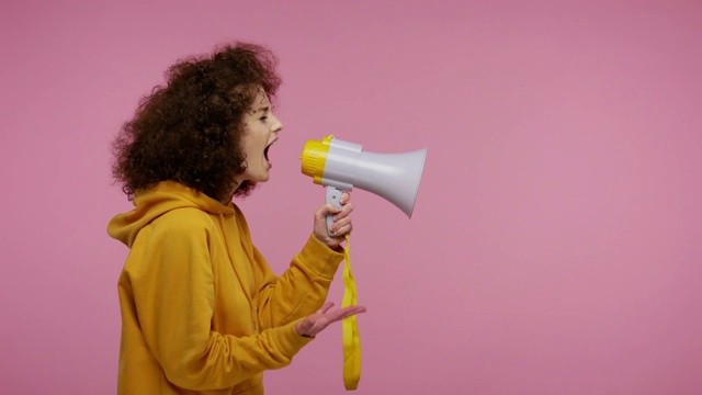 侧视图，穿着帽衫的非洲发型女孩用扩音器说话，宣布新闻，宣布广告视频素材