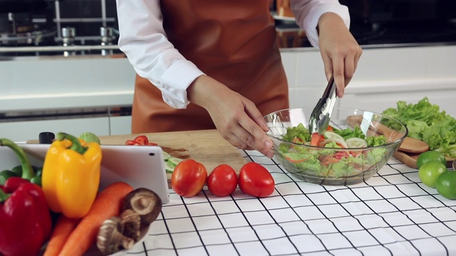 亚洲女性正在平板电脑上观看制作沙拉的食谱。视频素材