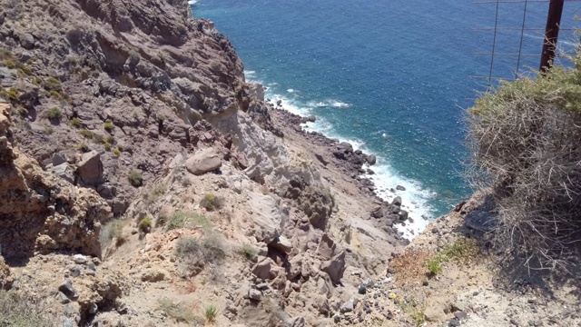 在圣托里尼岛，海浪拍打着火山口的岩石悬崖，冒险的夏季旅游度假视频素材