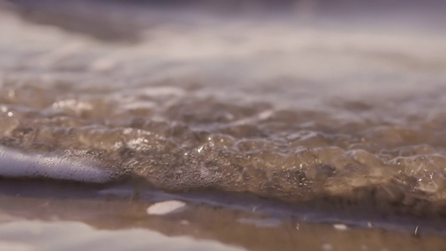 日落时海浪冲向海滩。慢动作海洋白色的水海浪拍击。视频下载