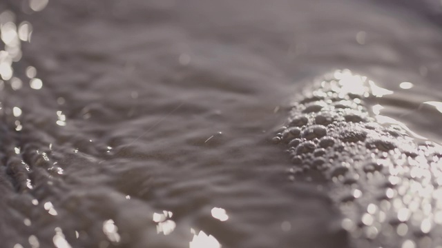 日落时海浪冲向海滩。慢动作海洋白色的水海浪拍击。视频下载