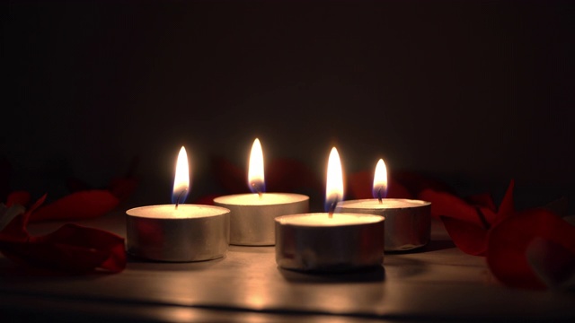 在黑暗的背景下吹灭玫瑰花瓣的浪漫蜡烛视频素材