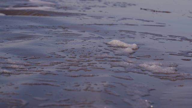 日落时海浪冲向海滩。慢动作海洋白色的水海浪拍击。视频下载