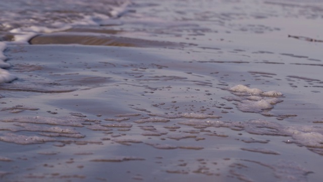 日落时海浪冲向海滩。慢动作海洋白色的水海浪拍击。视频下载