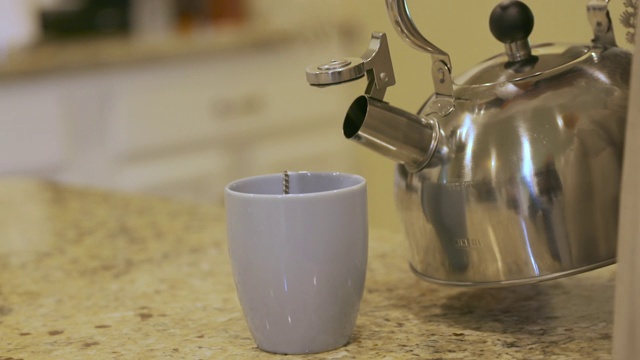 金属茶壶将绿茶倒入杯中。白色杯子和不锈钢茶壶或茶壶。视频素材