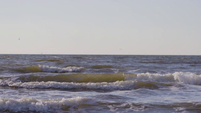 日落时海浪冲向海滩。慢动作海洋白色的水海浪拍击。视频素材