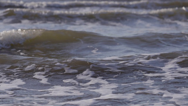 日落时海浪冲向海滩。慢动作海洋白色的水海浪拍击。视频下载