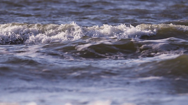 日落时海浪冲向海滩。慢动作海洋白色的水海浪拍击。视频下载