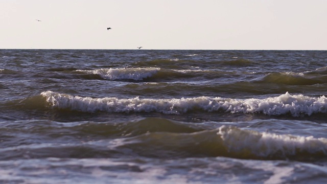 日落时海浪冲向海滩。慢动作海洋白色的水海浪拍击。视频素材