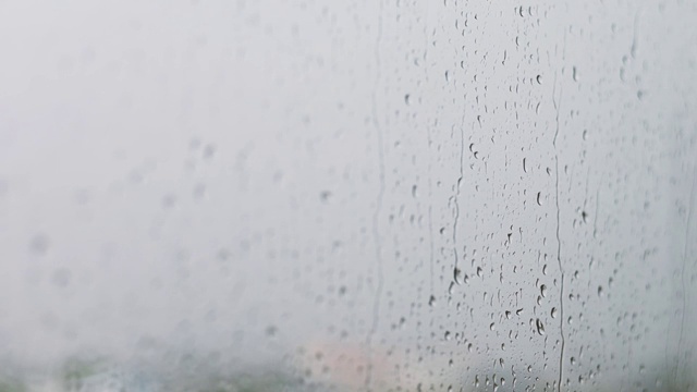 镜头选择焦点雨点与模糊的背景窗户，雨天，水滴玻璃，感觉孤独和悲伤的概念。坏天气的一天。看看窗外的景色，视频素材