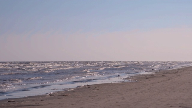 日落时海浪冲向海滩。慢动作海洋白色的水海浪拍击。视频下载