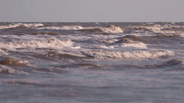 日落时海浪冲向海滩。慢动作海洋白色的水海浪拍击。视频素材