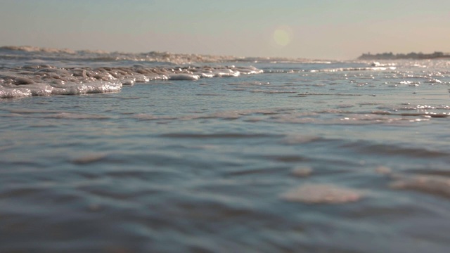 日落时海浪冲向海滩。慢动作海洋白色的水海浪拍击。视频素材